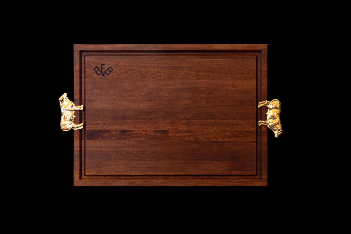 Pitmaster board in walnut, groove side up with two brass Bull handles and the Burnt End Boards mark burned into the face