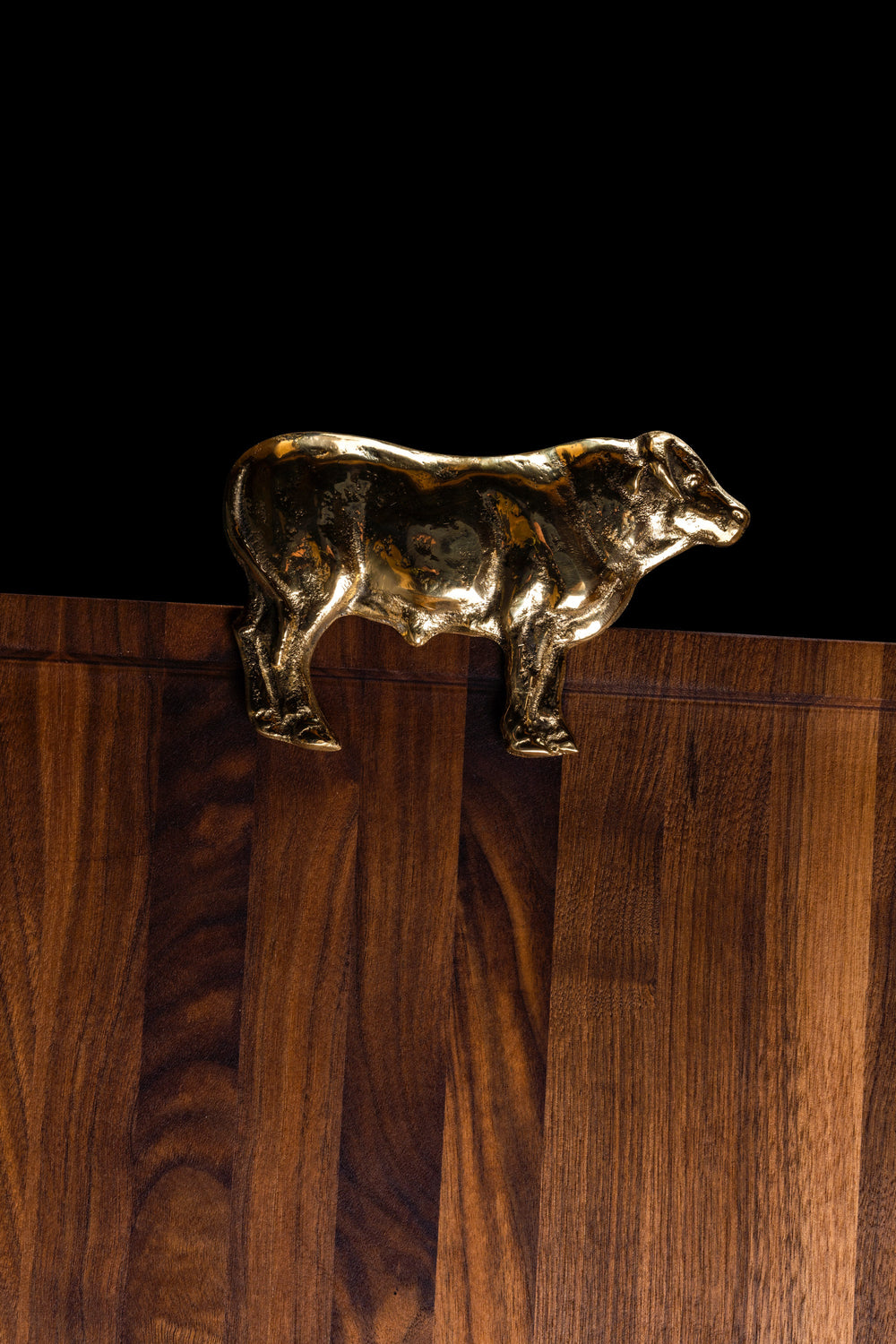 The Bull handle in brass, mounted on the edge of a walnut board